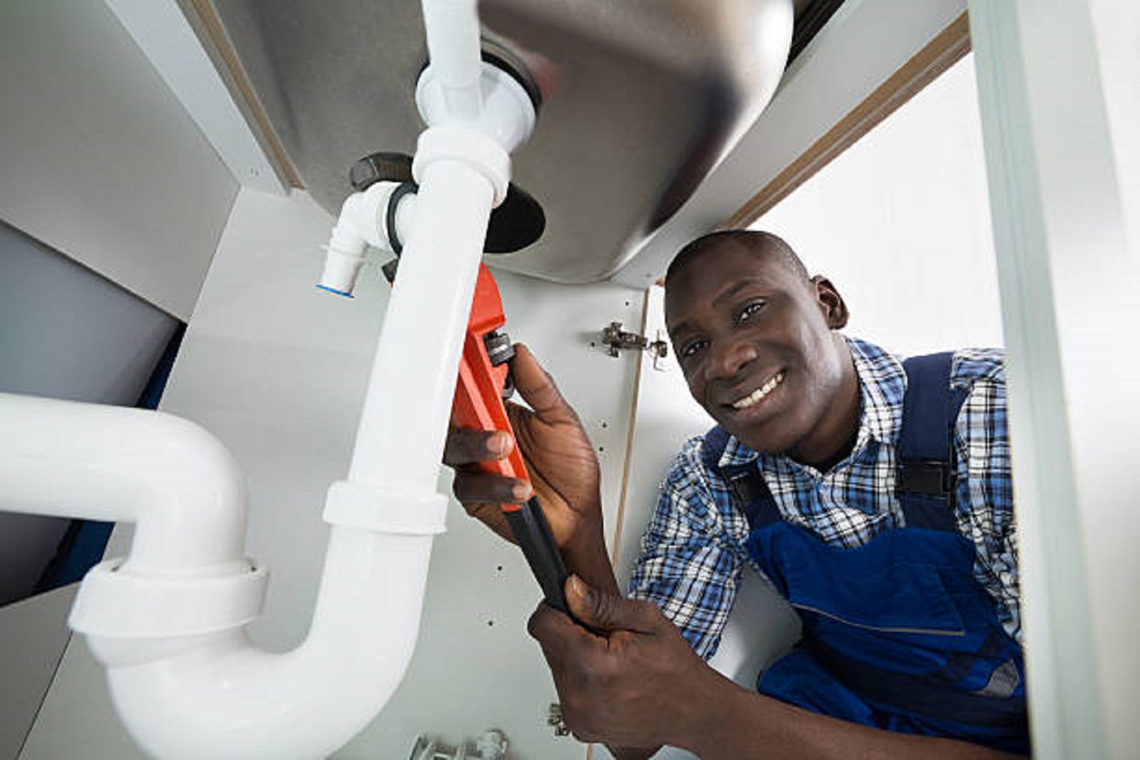 Young African Handyman Repairing Sink Pipe With Worktool